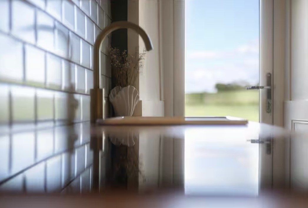 Brass tap and sink with a window onto the countryside