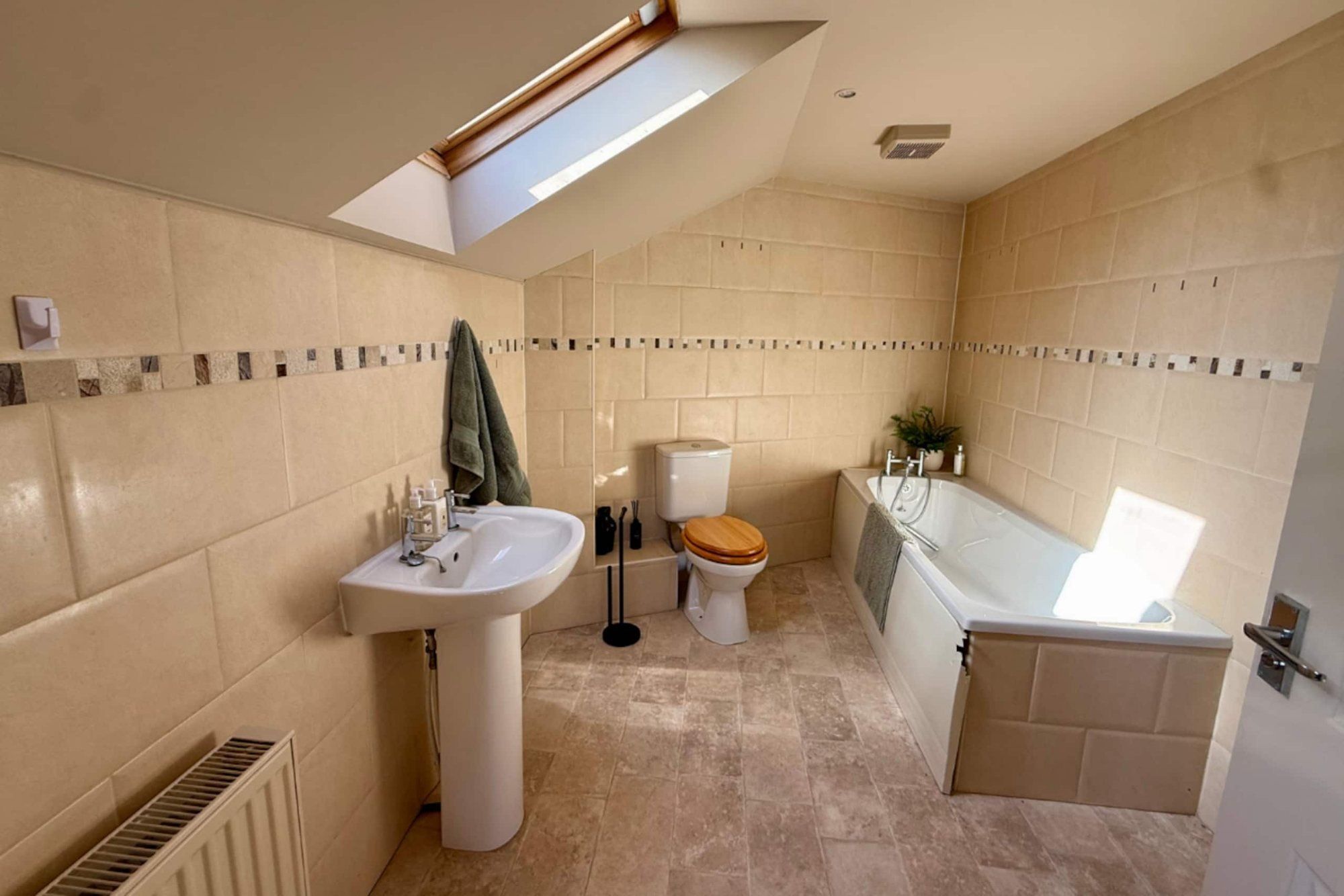 Bathroom with a bath, pedestal basin and roof window at Cranley Cottage