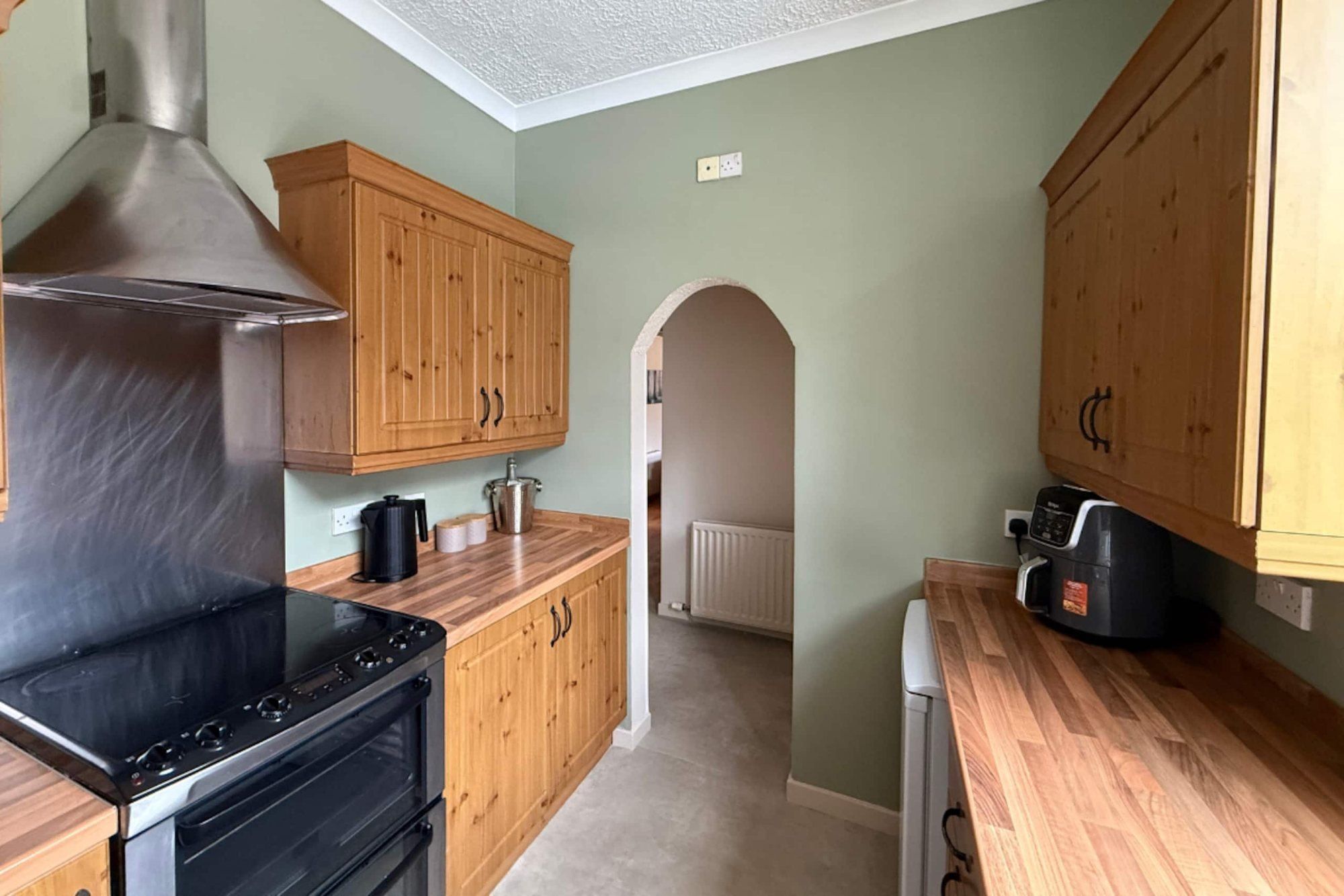 Cranley Cottage kitchen with pine cabinets, an electric range and an arched doorway