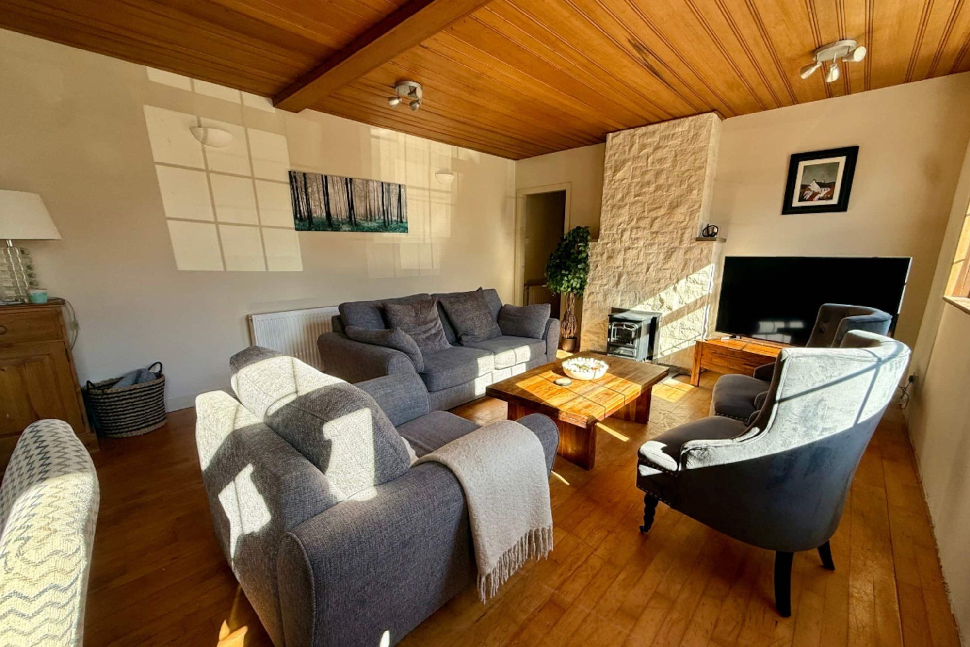 Sunlit living room at Cranley Cottage with a timber-clad ceiling and grey sofas