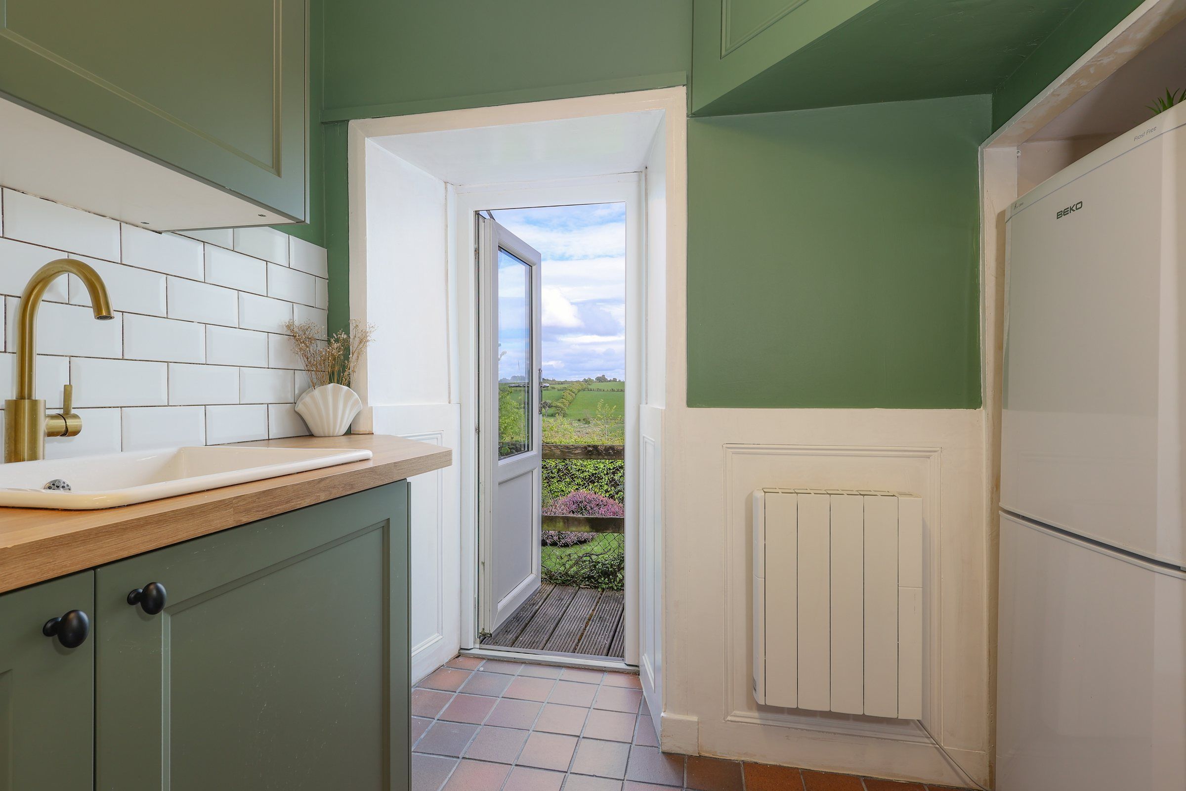 The kitchen door open onto a small deck, the garden and open farmland beyond